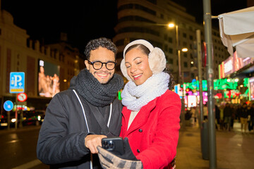Smiling couple taking selfie in vibrant city night