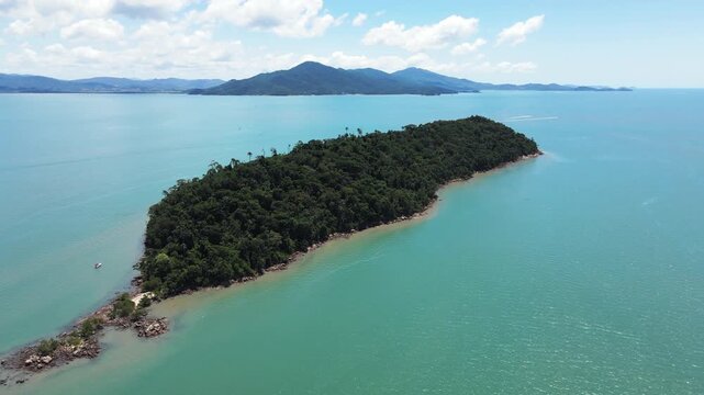 Aerial scene of Ratones Island in Florian&oacute;polis, Santa Catarina, full of trees and rocks of the Atlantic Forest with turquoise and cyan sea near Daniela Beach and mountain ranges on the horizon.
