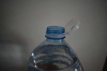 A close-up of a plastic water bottle with a flip-open white cap and threaded neck, The bottle style and cap mechanism resemble those commonly found in European water bottle designs