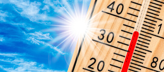 Ein Thermometer zeigt hohe Temperatur vor strahlender Sonne - FOTOMONTAGE