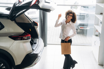 Obraz premium Trunk is opened. Pretty woman is in the car retail shop