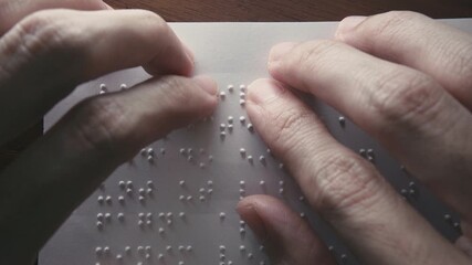 Visually impaired people use their fingertips to read Braille on paper. Text on the paper is a dummy Lorem ipsum text. - Powered by Adobe