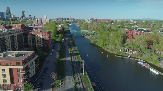 Aerial view of Lachine Canal in Montreal, Canada. People enjoy kayaking and paddle boating on a sunny day. The canal is a popular recreational area.
