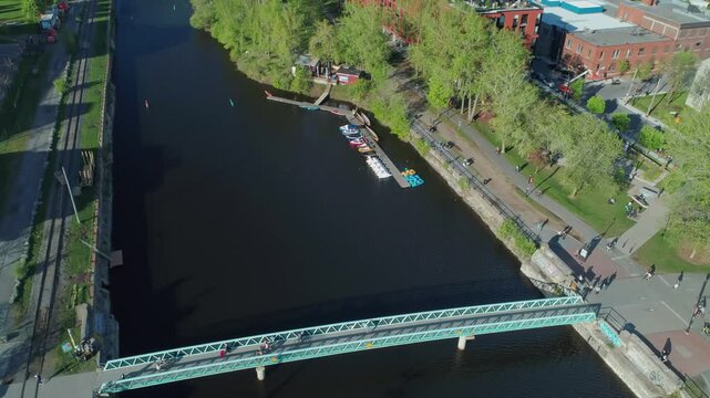 Aerial view of the Lachine Canal in Montreal, Canada. People are walking, biking, and boating along the canal for recreation and transportation.