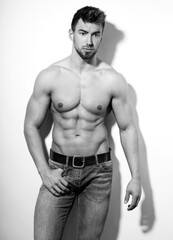 Fototapeta premium Handsome athletic man with muscular body and naked torso with six-pack wearing jeans