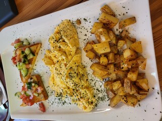 Breakfast plate with scrambled eggs, roasted potatoes and toast with fresh vegetables