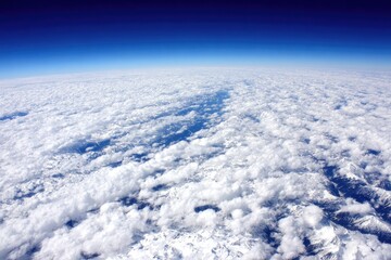 High-altitude view of puffy clouds, mountains, and a clear sky