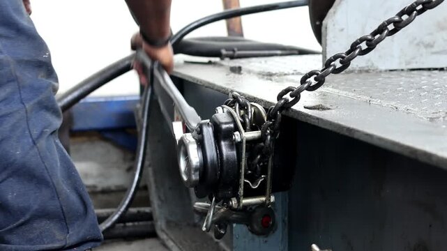 Male hand tightening the chain lever block hoist. Lever hoists are commonly used in various industries, including construction, mining, and manufacturing.
