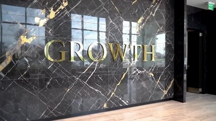 Modern interior features a dark marble wall with gold veining and metallic gold lettering spelling "GROWTH" above light wooden flooring - Powered by Adobe