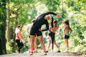 Against trees with green leaves. Group of runners are together outdoors