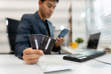Asian man stressed over credit card debt, holding bills in frustration. Financial anxiety and economic burden concept in a realistic lifestyle setting.	
