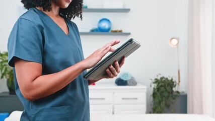 Diverse Woman Physiotherapist Using Digital Tablet for Patient Care and Clinic Management - Powered by Adobe
