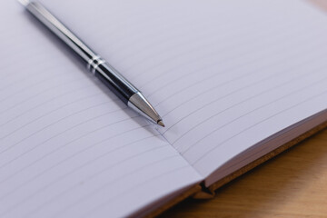 Writing and planning concept with a close-up of a pen resting on an open lined notebook, symbolizing creativity, note-taking, education, organization and preparation for personal or professional tasks