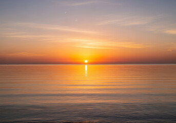 Obraz premium Calm ocean view at sunset with orange sky