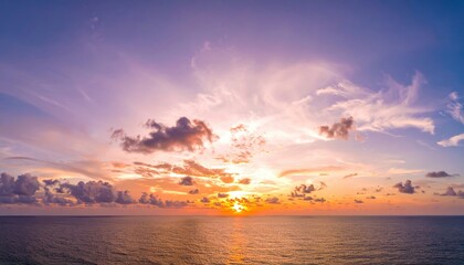 Obraz premium Sunset Serenity over the Ocean: A breathtaking panoramic view of the ocean at sunset, with the sky ablaze in vibrant hues of orange, pink, and purple, reflecting on the calm water.
