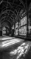 Fototapeta premium Sunlit stone corridor with arched ceiling, ribbed vaulting, and tall, narrow windows casting light patterns on the floor