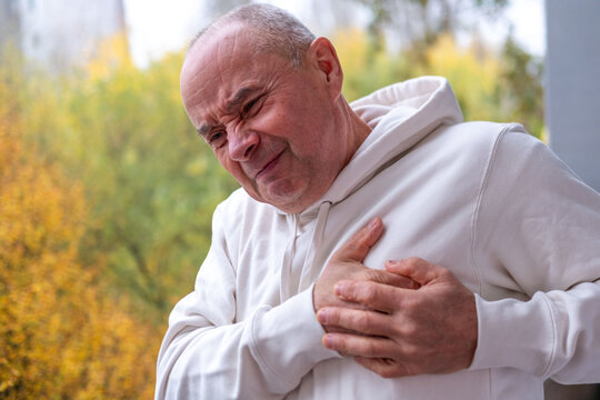 Bald man clutching chest in pain, sudden cardiac symptom, heart discomfort, possible rare cardiac condition, health risk, health emergency with worried expression, cardiac arrest