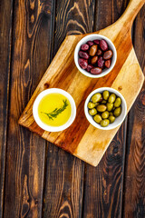 Olives and olive oil in white bowls, top view