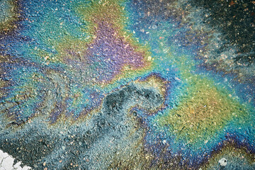 Colorful gasoline or oil spill creating a rainbow sheen on a wet asphalt road, illustrating pollution and environmental damage