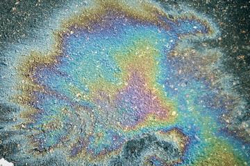 Colorful gasoline or oil spill creating a rainbow effect on asphalt, highlighting environmental pollution