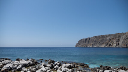 Rocky Shoreline with Clear Blue Sea and Coastal Cliffs

