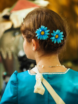 girl facing away from camera with two blue flowers in hair