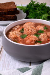 Soup with haddock fish balls in a gray bowl on white table
