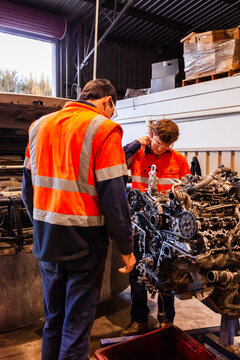 Two male mechanics inspecting vehicles engine in workshop