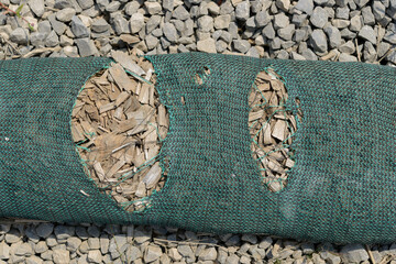 prefilled silt sock with wood chips and runs large enough to fit an arm outdoors on a ground of stone gravel