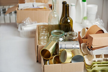 Sorting garbage for recycling. Cardboard boxes with various garbage, paper, cardboard, tin cans, glass bottles. Waste sorting, waste recycle. Garbage separation concept.