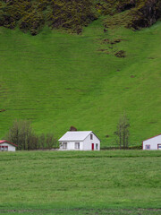 A white house surrounded by mountain and green field.