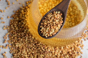 Raw buckwheat tea in a bowl with a spoon. Uncooked buckwheat grain in the bowl. 