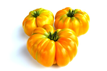 Three ribbed yellow-orange heirloom tomatoes on clean white background