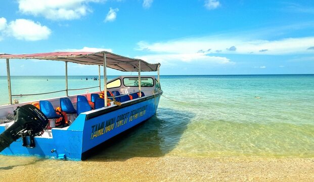 Rameswaram, Tamil Nadu, India &ndash; April 5, 2025: A Tamil Nadu Forest Department passenger boat anchored at the shore of Ariyaman Beach under clear blue skies and calm turquoise waters.