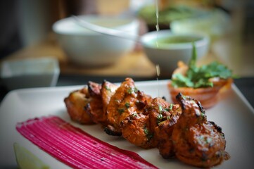 Chicken tikka or chicken kebab served on white plate in a restaurant background
