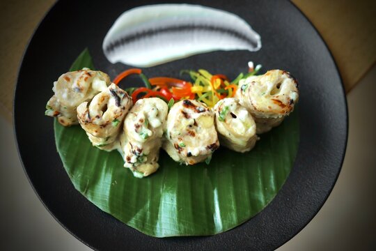 Soya chaap garnished with veggies on a black plate