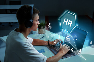 Individual working on laptop with HR technology concept in a modern office setting during evening...