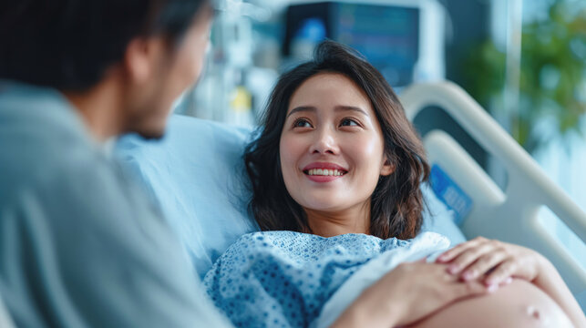 Smiling pregnant woman in hospital bed looking at partner, expressing love, anticipation and happiness during labor and childbirth.