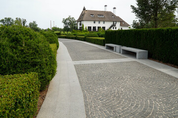A paved path in the park and a house next to it