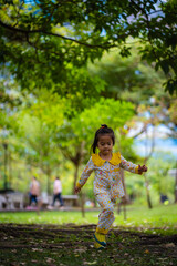 Little kid girl running on green meadow city park
