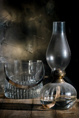 Kerosene lamp on rustic table against dark wall