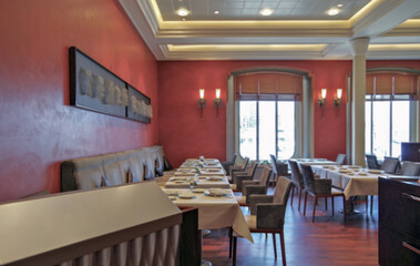 Formal and elegant a la carte speciality ocean view dining room restaurant onboard luxury cruiseship or cruise ship liner with set tables in red white interior design style and ceiling ambient light