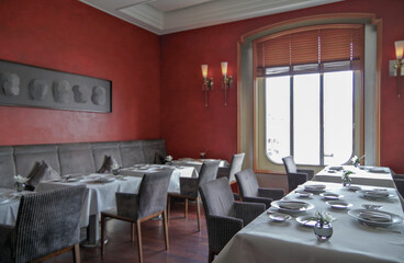 Formal and elegant a la carte speciality ocean view dining room restaurant onboard luxury cruiseship or cruise ship liner with set tables in red white interior design style and ceiling ambient light