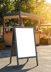 A blank A-frame sign mockup stands on a sunny city street in front of an outdoor coffee kiosk.