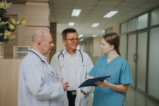 Doctor and nurse reviewing patient record in hospital hallway. Group of healthcare professionals discussing medical records on a clipboard in hospital, collaborating on patient care