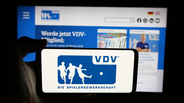 Stuttgart, Germany - 08-07-2025: Person holding cellphone with logo of Vereinigung der Vertragsfu&szlig;ballspieler (VDV) on screen in front of webpage. Focus on phone display.