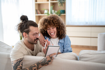 Happy couple planning and laughing together on sofa at home