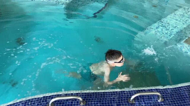 Child swimming in indoor pool, swimming lessons for kids