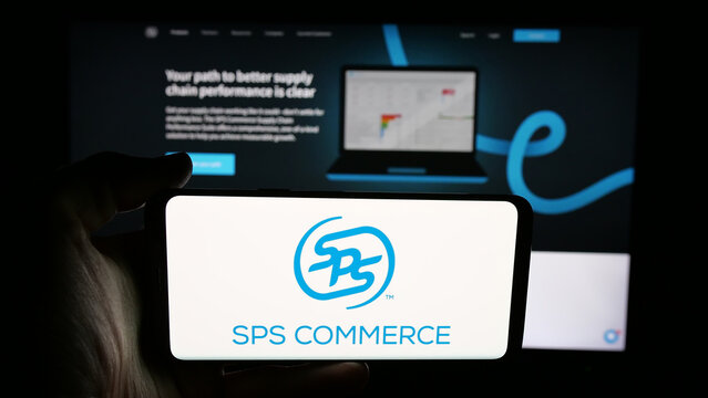 Stuttgart, Germany - 08-07-2025: Person holding cellphone with logo of US software company SPS Commerce Inc. on screen in front of webpage. Focus on phone display.
