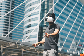 Young man wearing VR headset and interacting with virtual environment outdoors in a modern city. Concept of immersive technology, digital future, virtual navigation, and smart lifestyle.
